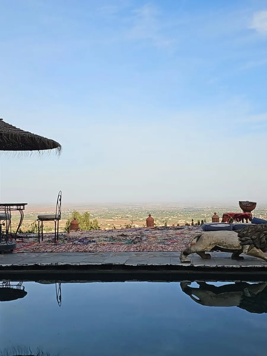 Terrasse marocaine où les tapis sont étendus au soleil, face aux montagnes de l’Atlas